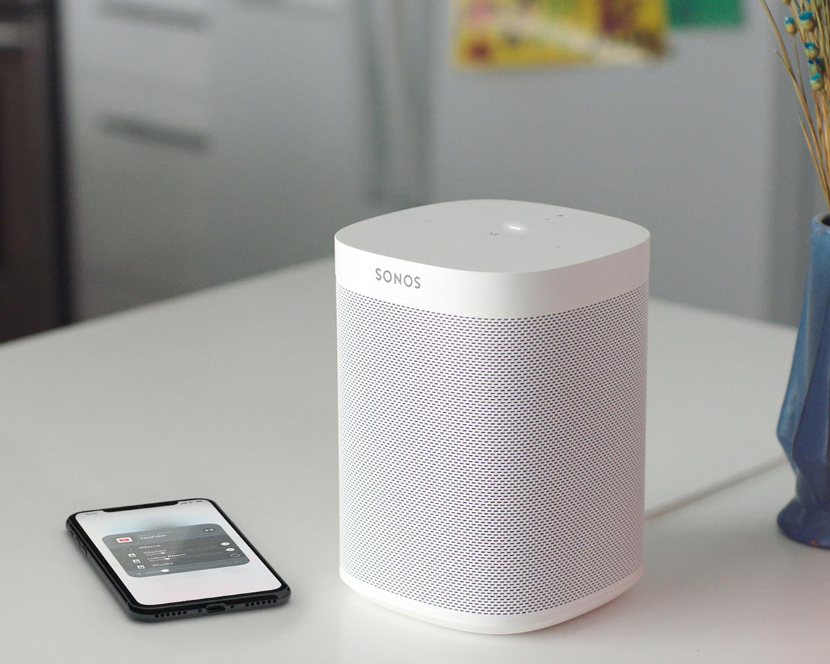 Bluetooth sonos speaker on top of white table next to a cellphone